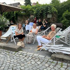 ein Schotterplatz, darauf stehen die Liegestühle im Vordergrund 3 Frauen die in Liegestühlen sitzen