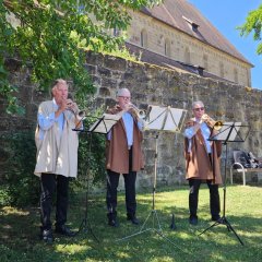 Drei Musiker spielen Blasinstrumente im Freien.
