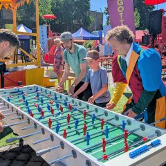 Drei Erwachsene und ein Kind beim Tischkicker spielen