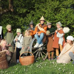 Beflaggung zum Bauernkrieg Auf dem Bild zu sehen sind 11 Kinder, die bäuerlich gekleidet sind. Im Vordergrund des Bildes stehen zwei Weidenkörbe. An der linken Bildseite steht ein gewandeter Mann mit einem Ablassbrief.