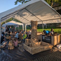 Kinder bauen unter einem Zelt mit Holzklötzen.