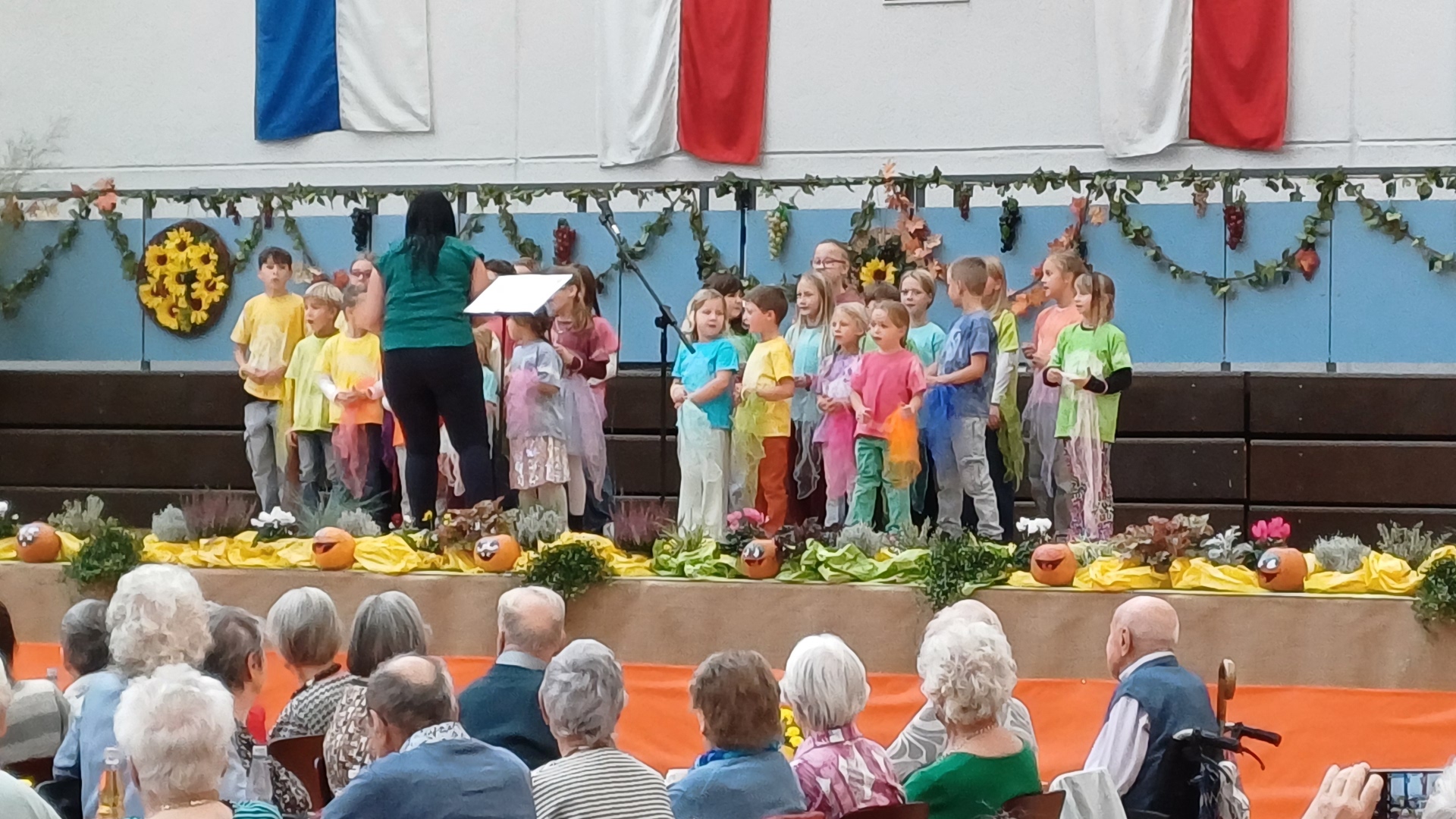 Ca. 25 singende Chorkinder halten bunte Tücher in der Hand.