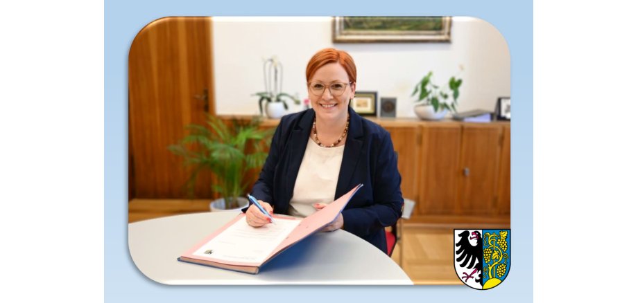 Weinsbergs Bürgermeisterin Birgit Hannemann sitzt an einem Tisch und unterschreibt ein Dokument.
