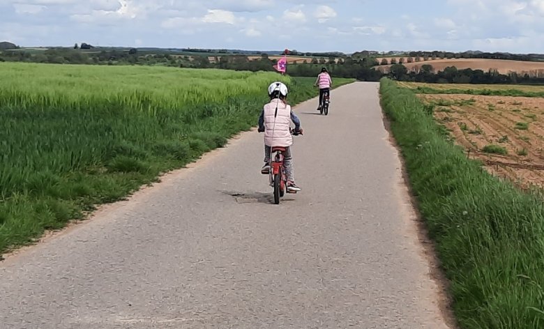 Feldweg mit 2 radelnden Kindern von hinten fotografiert