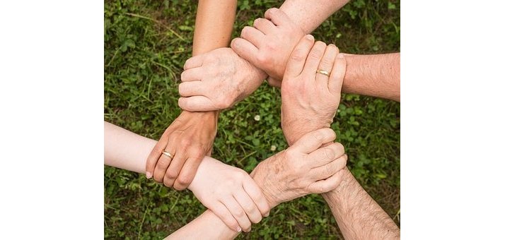 6 Hände greifen im Kreis an die Handgelenke